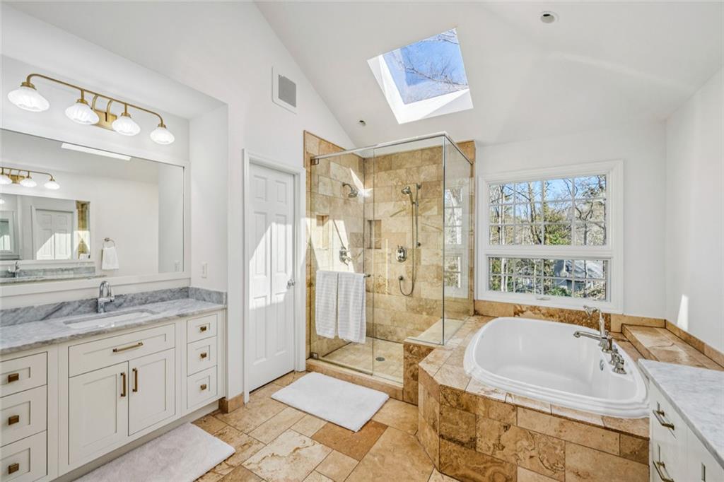 4575 Jett Road Atlanta, GA 30327 - Photo 21 of 42 a spacious bathroom with a granite countertop tub sink a mirror a shower and vanity