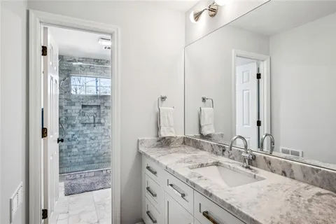 a bathroom with a granite countertop sink a mirror and shower