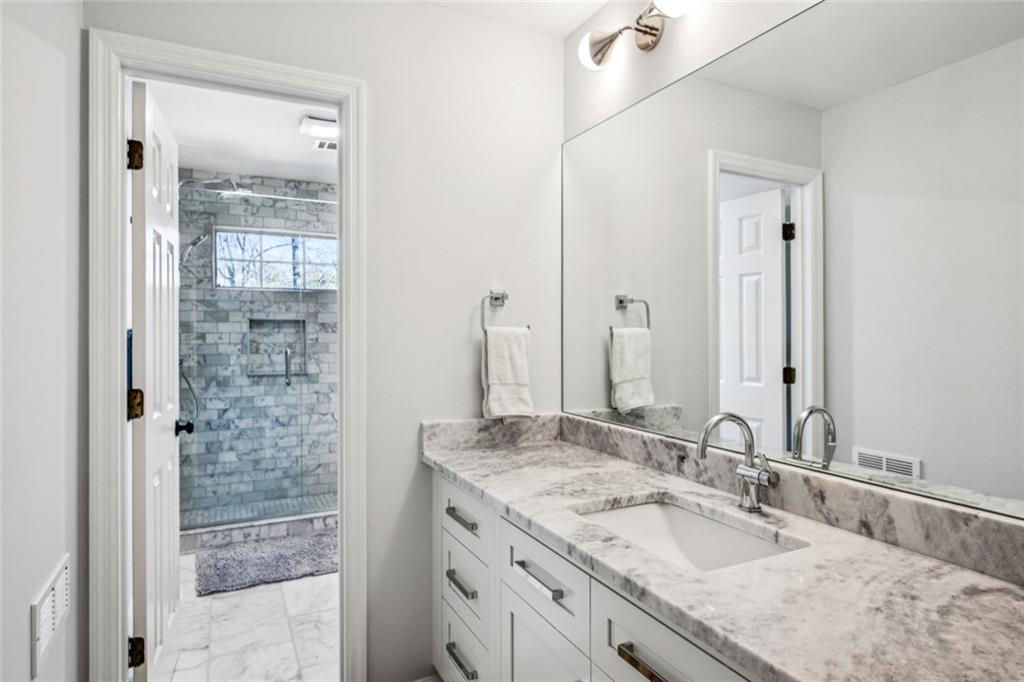 4575 Jett Road Atlanta, GA 30327 - Photo 24 of 42 a bathroom with a granite countertop sink a mirror and shower