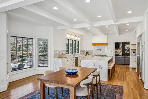 a kitchen with stainless steel appliances kitchen island granite countertop a refrigerator a stove top oven a dining table and chairs with wooden floor