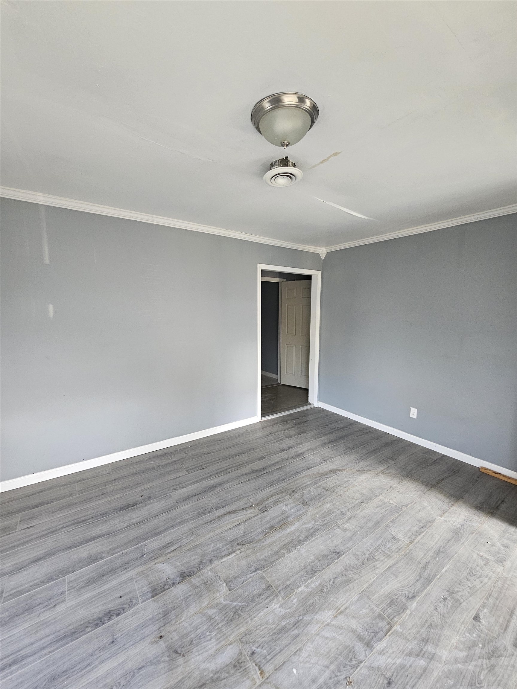 2059 Swift Street Memphis, TN 38109 - Photo 3 of 12 Spacious room featuring gray walls, wood-finish flooring, white crown molding, a ceiling fan with integrated lighting, and a white interior door