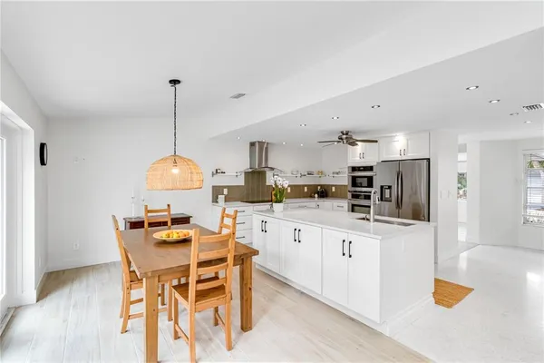 a kitchen with stainless steel appliances kitchen island granite countertop a sink a stove a dining table and chairs