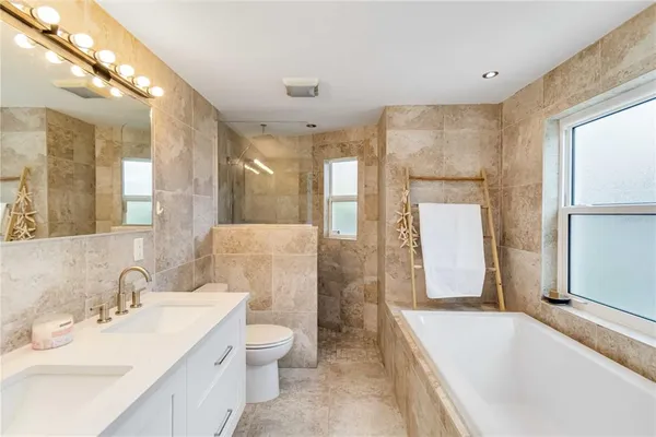 a spacious bathroom with a double vanity sink toilet mirror and bathtub
