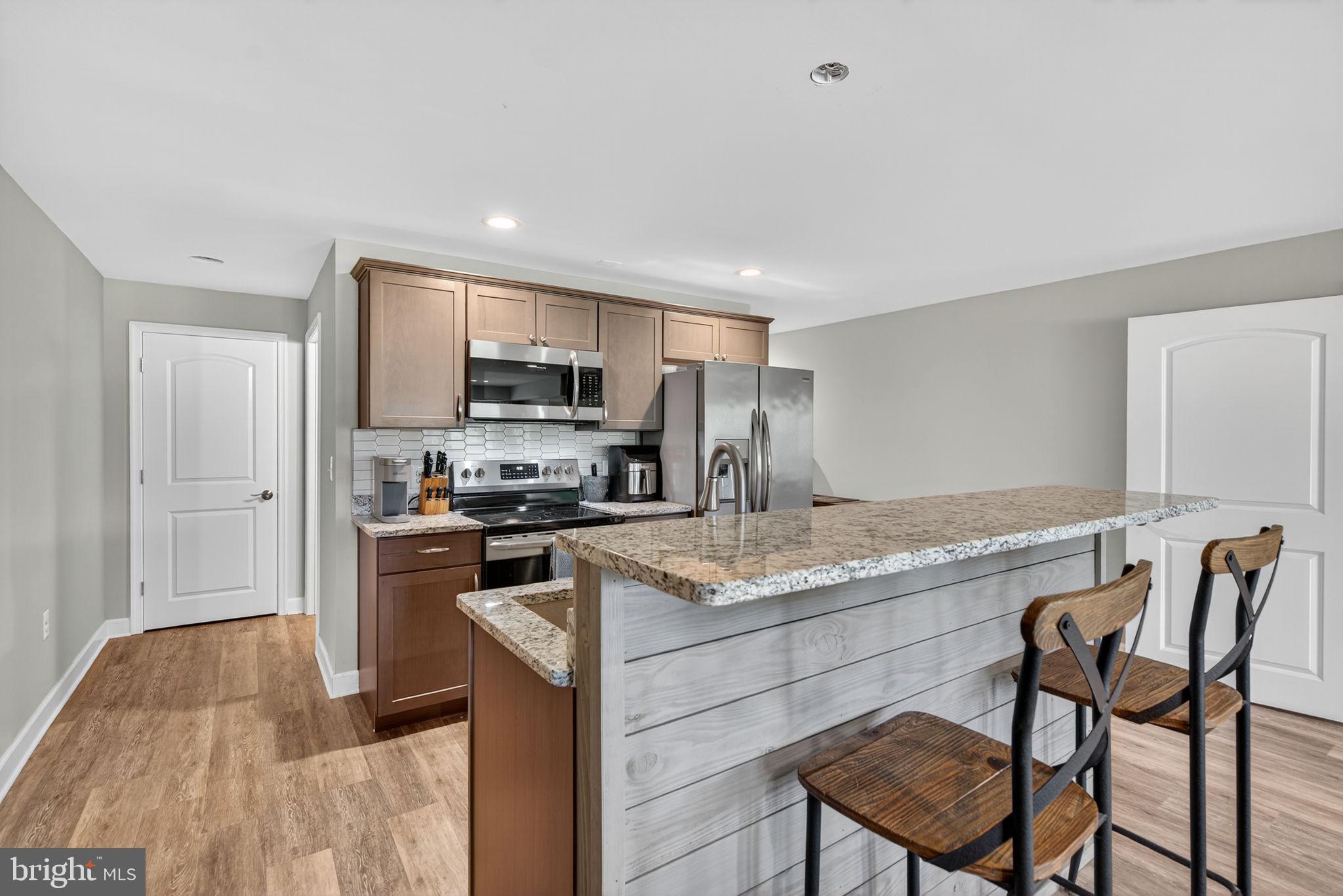 14451 Jenkins Ridge Road Culpeper, VA 22701 - Photo 37 of 78 a kitchen with kitchen island granite countertop wooden cabinets a stove a microwave a island with a dining table and chairs