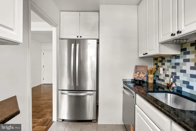 a kitchen with stainless steel appliances granite countertop a refrigerator a sink and white cabinets