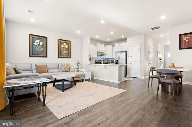 a living room with stainless steel appliances kitchen island granite countertop furniture and wooden floor
