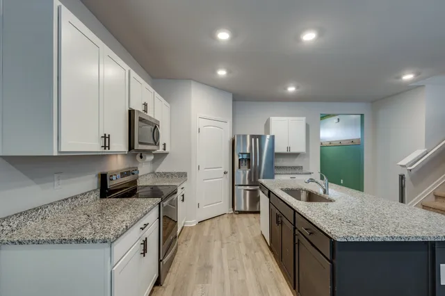 a kitchen with stainless steel appliances granite countertop a sink a stove and a refrigerator