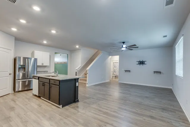 an empty room with wooden floor ceiling fan and windows
