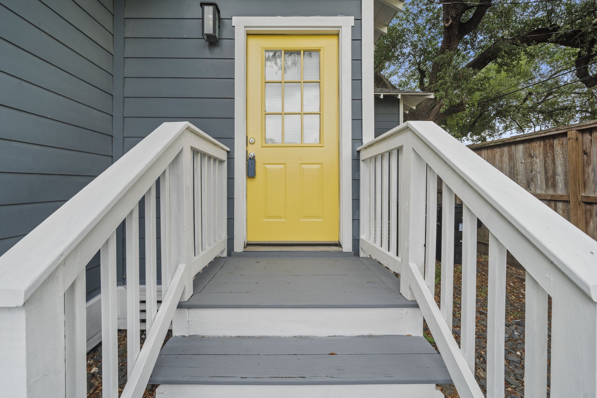 4734 Bell Street, Unit B Houston, TX 77023 - Photo 3 of 10 Rear entry detail with yellow door, white railings, and covered landing for a clean, welcoming arrival.