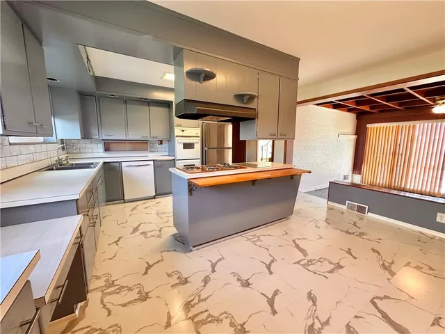 a kitchen with stainless steel appliances kitchen island granite countertop a sink and cabinets