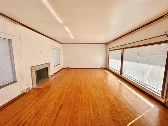 a view of empty room with wooden floor and fireplace