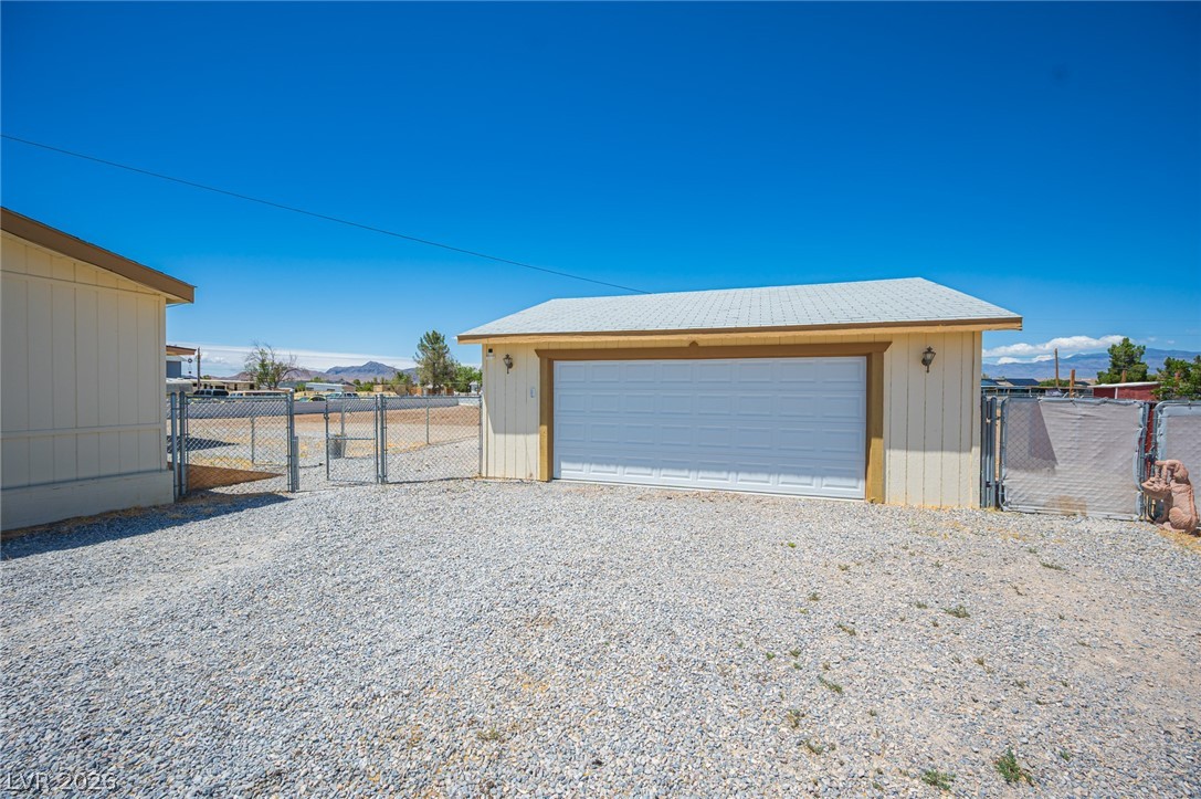 3200 Maple Road Pahrump, NV 89048 - Photo 4 of 53 A detached garage provides ample space for vehicles and storage, complementing the vast gravel lot.