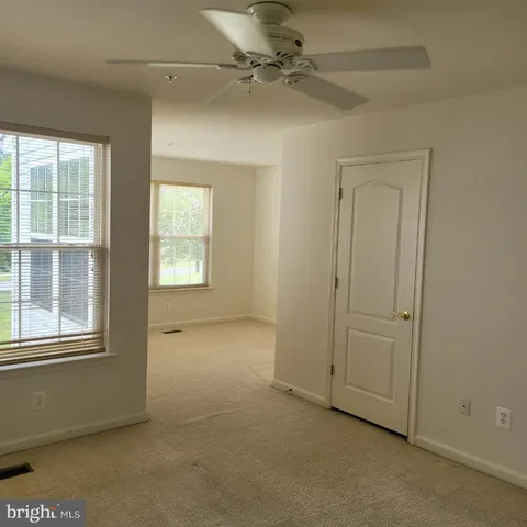 an empty room with windows and fan