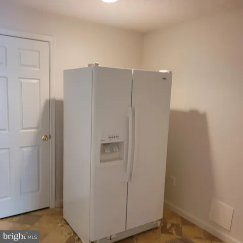 a view of a refrigerator in kitchen and white cabinets