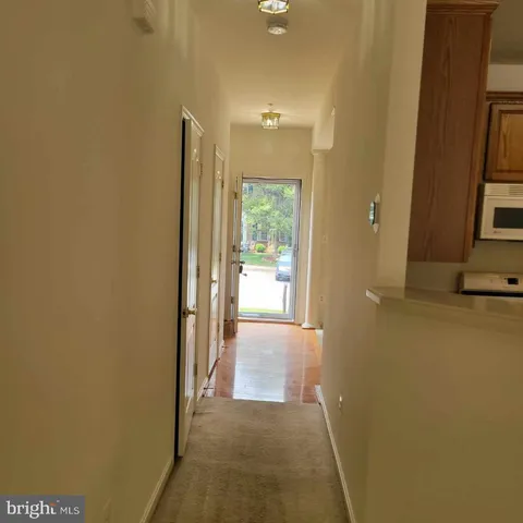 a view of a hallway with wooden floor and a bathroom