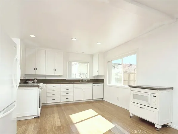 a kitchen with granite countertop white cabinets and white appliances