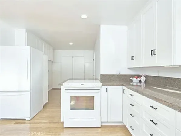 a kitchen with cabinets appliances and wooden floor