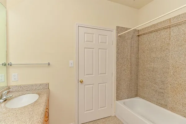 a bathroom with a granite countertop tub sink and mirror
