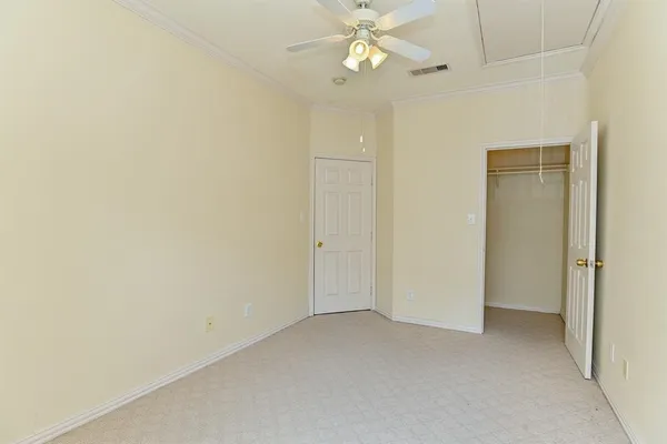 an empty room with a chandelier fan and closet area