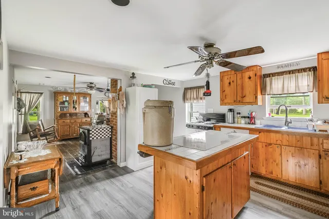 a kitchen with stainless steel appliances granite countertop a refrigerator a sink dishwasher a stove and white countertops with wooden floor