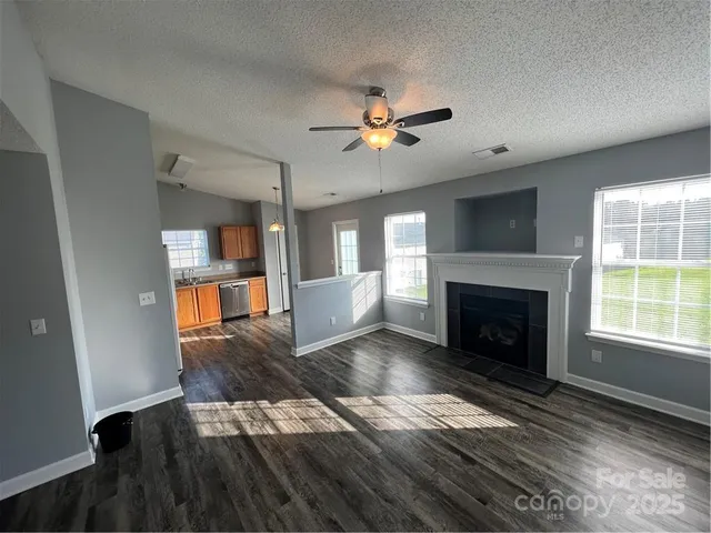 a view of a livingroom with wooden floor a fireplace and a window