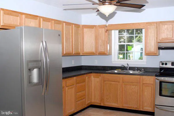 a kitchen with stainless steel appliances granite countertop a sink a stove and refrigerator