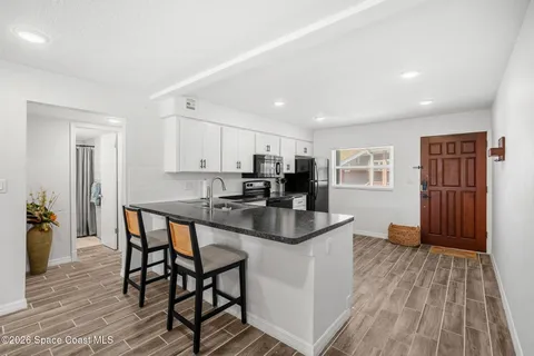 a kitchen with stainless steel appliances kitchen island granite countertop a dining table chairs and a refrigerator