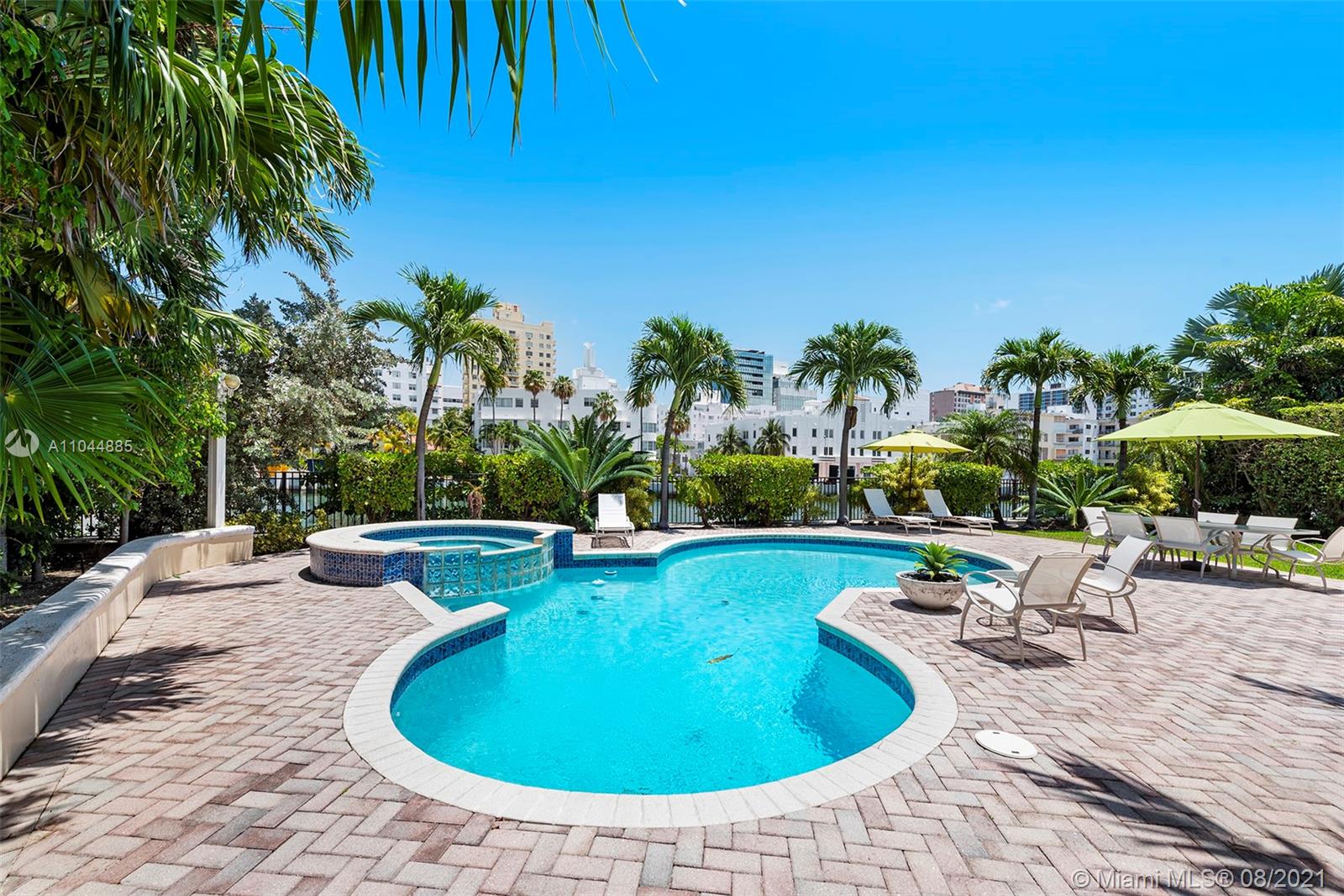 2995 Flamingo Drive Miami Beach, FL 33140 - Photo 19 of 54 a view of a swimming pool with lawn chairs under an umbrella