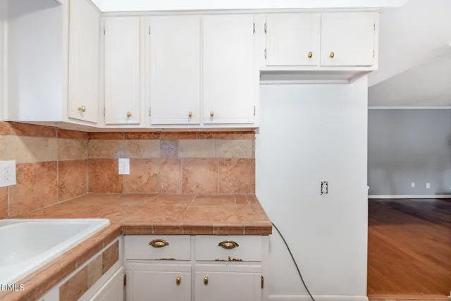 a view of kitchen with granite countertop white cabinets and a wooden floor