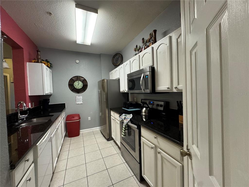 7664 Comrow Street, Unit 204 Kissimmee, FL 34747 - Photo 2 of 17 a kitchen with stainless steel appliances a stove a sink and a refrigerator