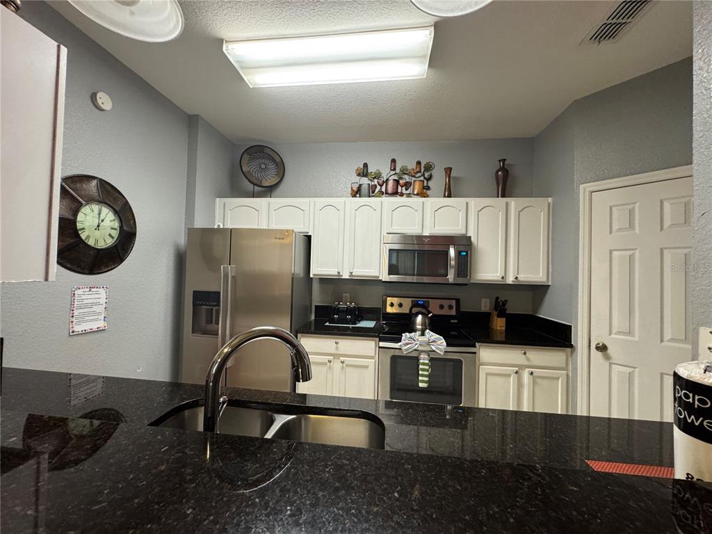 7664 Comrow Street, Unit 204 Kissimmee, FL 34747 - Photo 3 of 17 a view of a kitchen with stainless steel appliances granite countertop a stove top oven a sink and cabinets