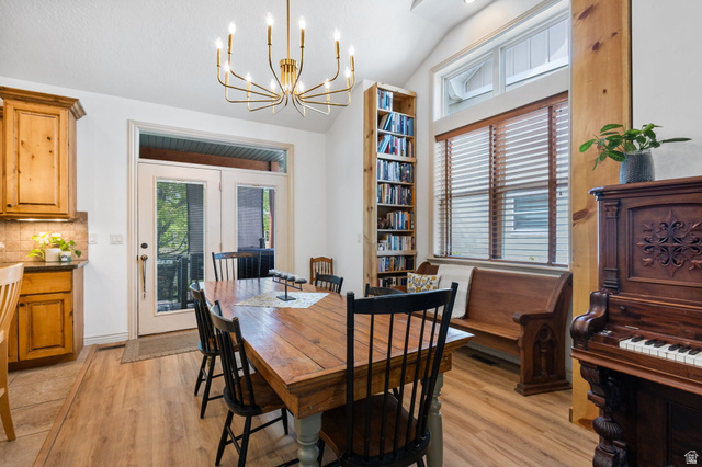 882 Sego Lily Way Mapleton, UT 84664 - Photo 8 of 41 Dining area featuring wood-finish flooring, a contemporary chandelier, vaulted ceilings, and a built-in bookshelf