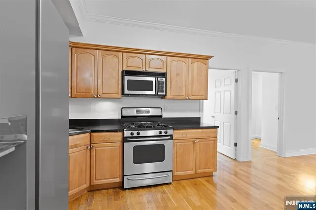 a kitchen with stainless steel appliances wooden floor sink and wooden cabinets