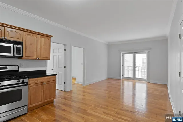 a kitchen with granite countertop a stove a microwave and a hard wood floors