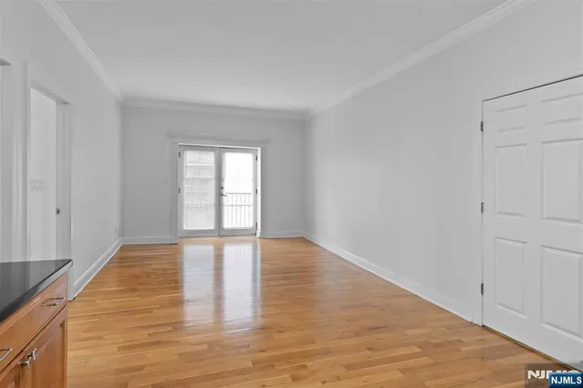 a view of an empty room with wooden floor and window