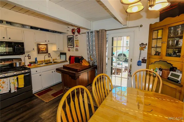 a kitchen with stainless steel appliances granite countertop a stove a sink a dining table and chairs with wooden floor