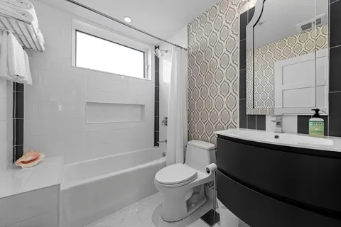 a bathroom with a toilet a sink a mirror a bathtub and shower