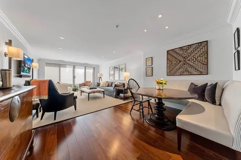 a living room with furniture kitchen view and a wooden floor