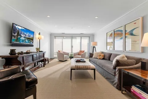 a living room with furniture two windows and a flat screen tv