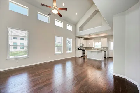 a view of an empty room with a kitchen and wooden floor