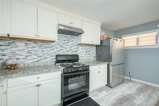 a kitchen with granite countertop a stove sink and refrigerator