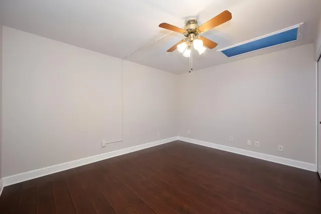 an empty room with wooden floor and ceiling fan