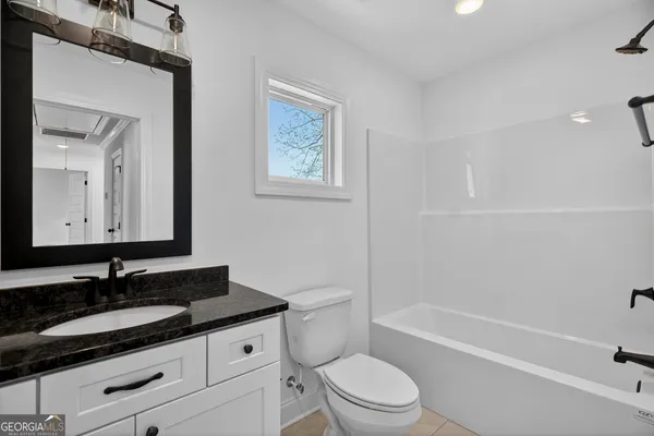 a bathroom with a granite countertop sink toilet a mirror and bathtub