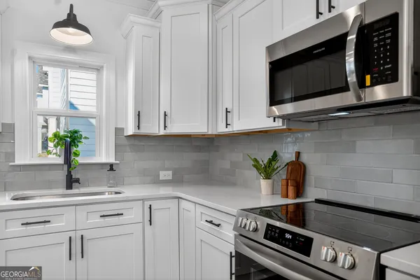 a kitchen with stainless steel appliances white cabinets and a stove top oven