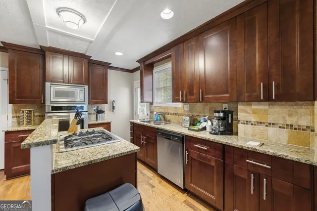 a kitchen with granite countertop wooden cabinets stainless steel appliances a sink and a counter top space