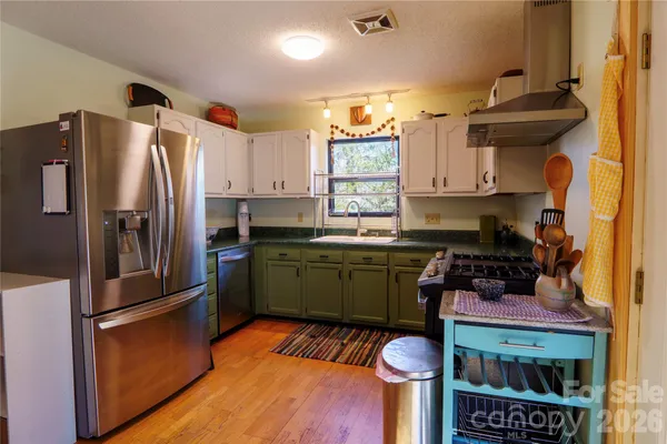 a kitchen with stainless steel appliances granite countertop a refrigerator a sink dishwasher a stove and a dining table with wooden floor