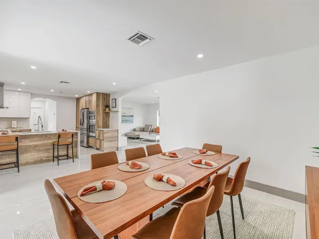 a view of a dining room and livingroom with furniture wooden floor a rug and a chandelier