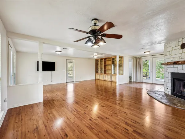 a view of an empty room with wooden floor fireplace and a window