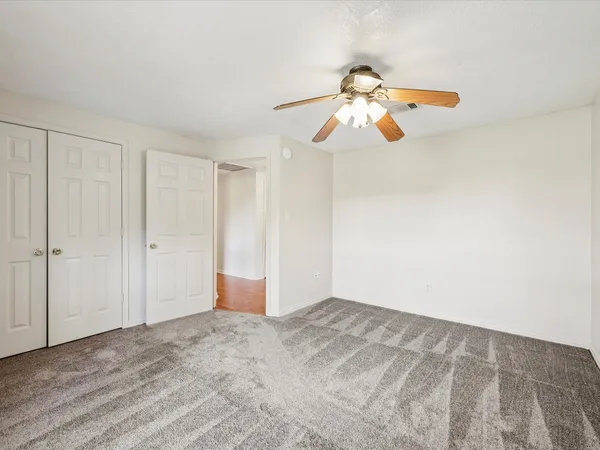 an empty room with ceiling fan and window