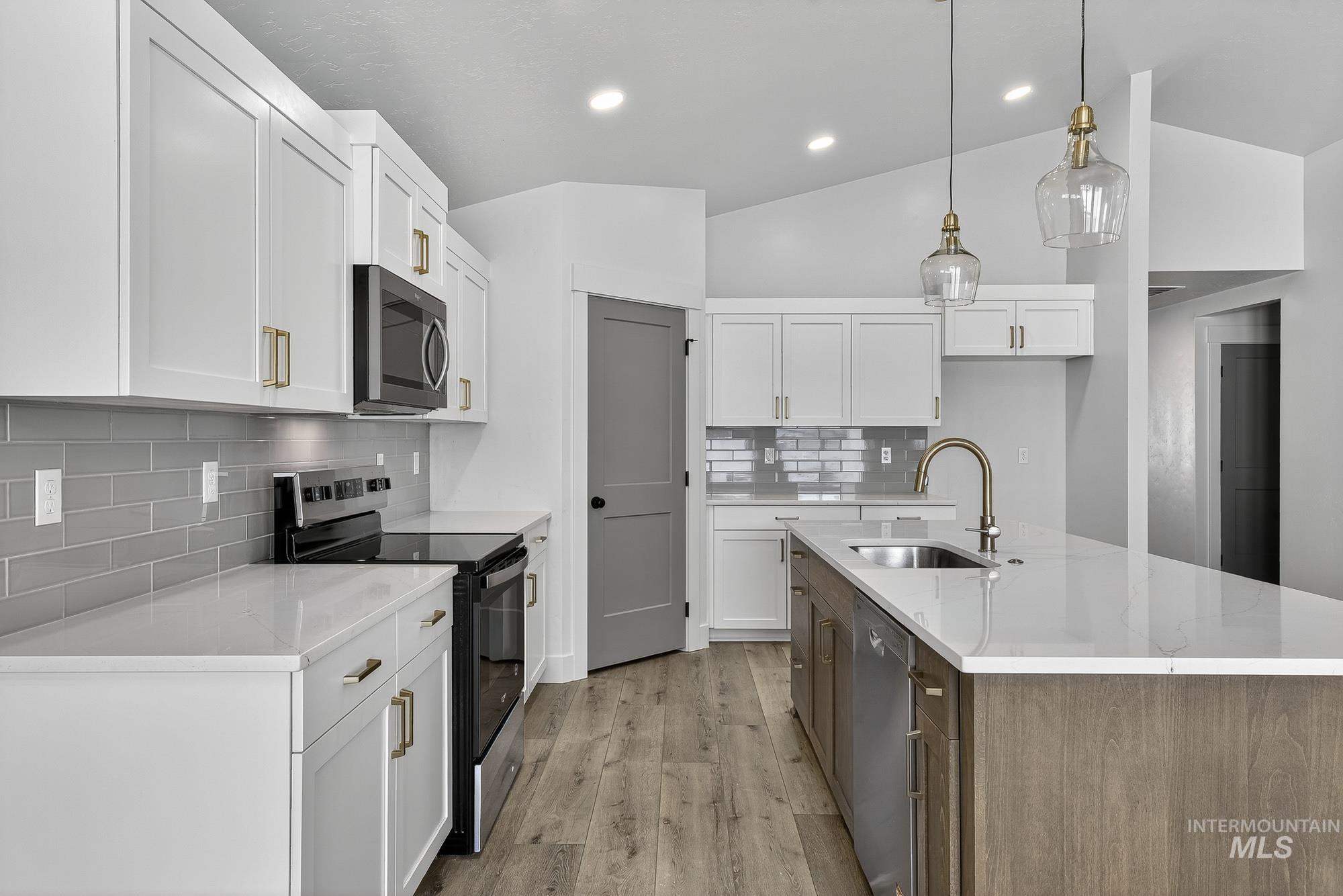 1158 Velvet Loop Wilder, ID 83676 - Photo 10 of 34 Kitchen featuring stainless steel appliances, pendant lighting, white cabinetry, vaulted ceiling, and a center island with sink